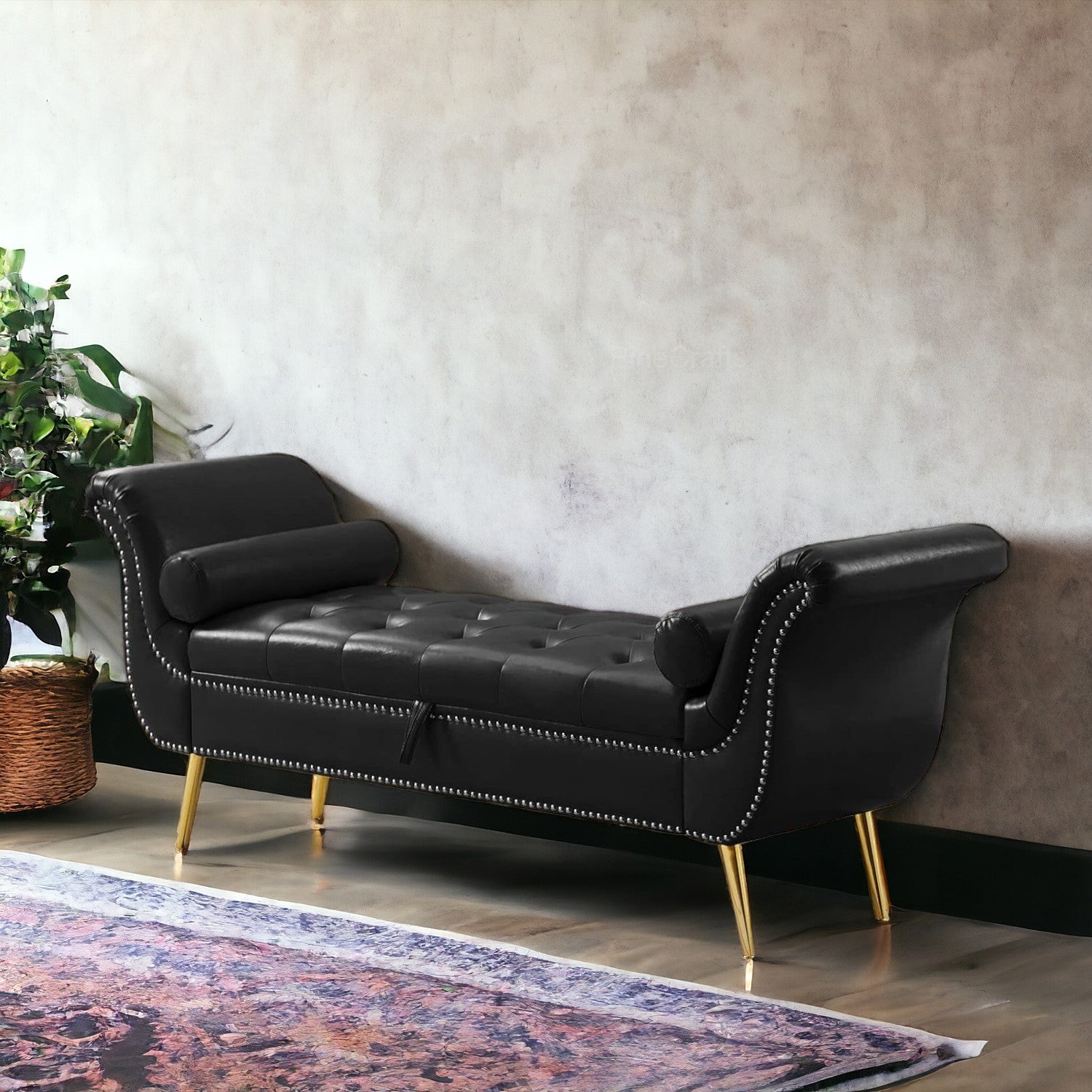 A black velvet button tufted 3-seater sofa with gold legs, placed in a living room setting with a grey throw blanket and a decorative plant in the background.